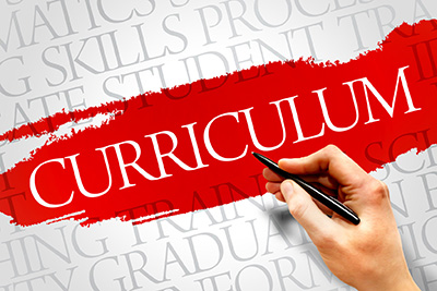 A hand holding a pen, highlighting the word 'CURRICULUM' in red.